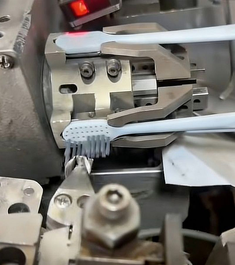 Machine for implanting bristles into the handle of acetate toothbrushes